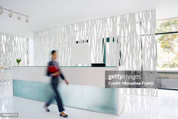 businesswoman rushing through office lobby - busy lobby stock pictures, royalty-free photos & images