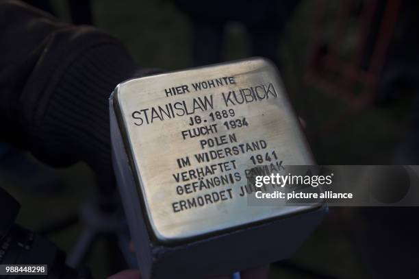 Stolperstein' with the name of Stanislaw Kubicki is held up before being let into the ground at the Onkel-Braesig-Strasse in the district of Britz in...