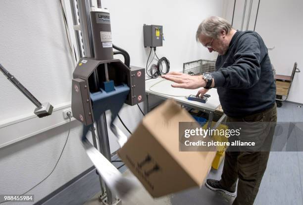 The packaging examiner Uwe Moeller testes a package by dropping it on the ground at the package check station of the German Post in Darmstadt,...