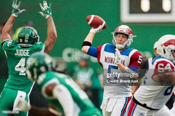 Drew Willy of the Montreal Alouettes attempts a pass over the rushing Cameron Judge of the Saskatchewan Roughriders in the game between the Montreal...
