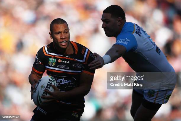 Moses Mbye of the Tigers takes on the defence during the round 16 NRL match between the Wests Tigers and the Gold Coast Titans at Leichhardt Oval on...