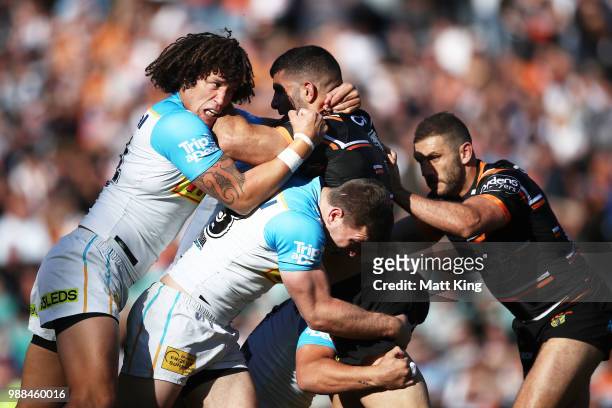 Alex Twal of the Tigers is tackled by Kevin Proctor of the Titans during the round 16 NRL match between the Wests Tigers and the Gold Coast Titans at...
