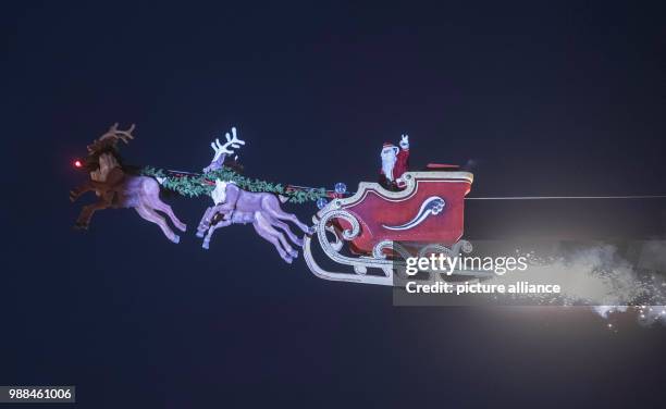 The high-wire artist Falko Traber drives in a motor-powered sled dressed as Father Christmas above the Christmas market in Karlsruhe, Germany, 05...