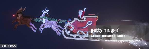 The high-wire artist Falko Traber drives in a motor-powered sled dressed as Father Christmas over the Christmas market in Karlsruhe, Germany, 05...