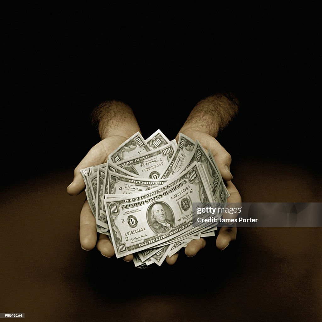 Hand holding one hundred dollar bills