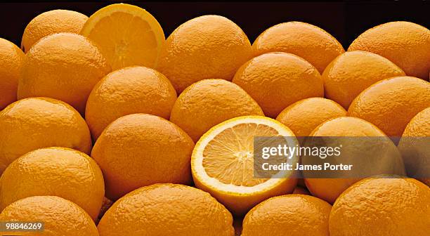 sliced orange among whole ones - james hale stock pictures, royalty-free photos & images