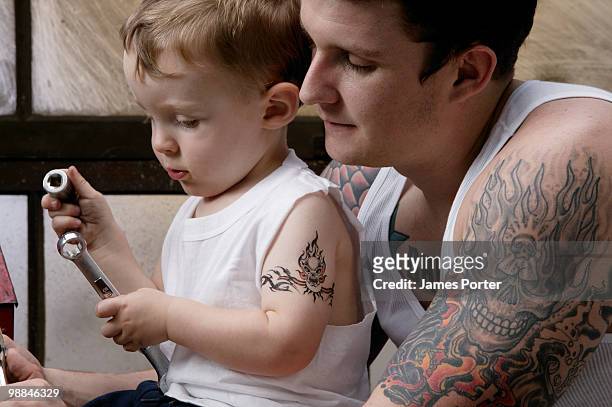 boy holding wrench and father watching - leanintogether stock pictures, royalty-free photos & images