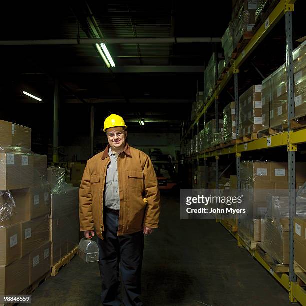 worker holding lunchbox standing in a warehouse - vrachtruimte stockfoto's en -beelden