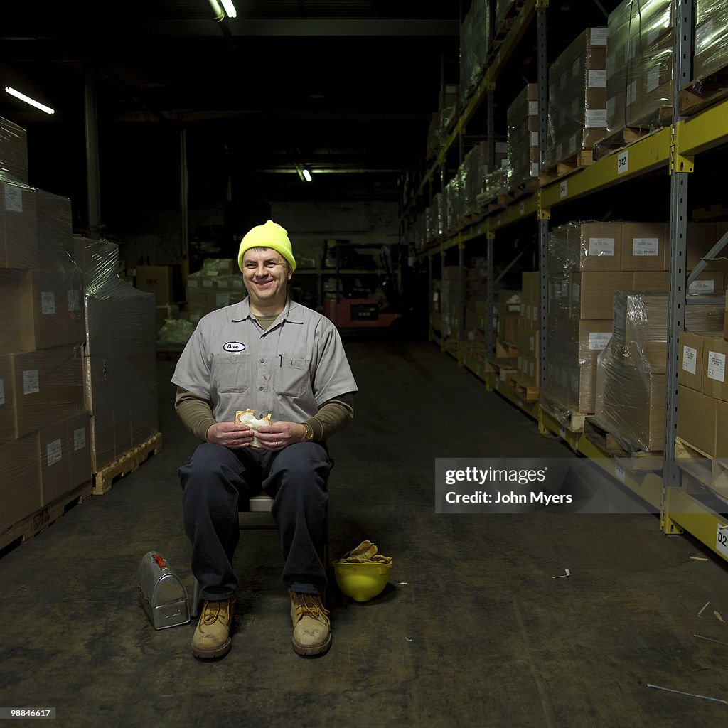 Manual laborer in warehouse eating lunch