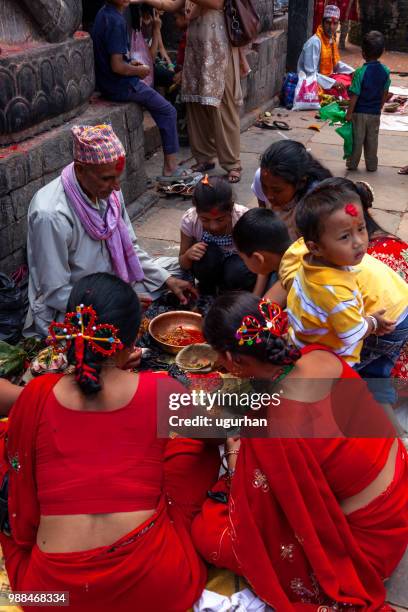 nepalese prophet and women clad in red traditional clothing on religious event in temple. - clad stock pictures, royalty-free photos & images