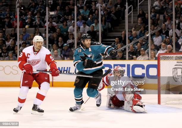 Joe Thornton of the San Jose Sharks races after the puck while defended by Nicklas Lidstrom and Jimmy Howard plays in the goal for the Detroit Red...