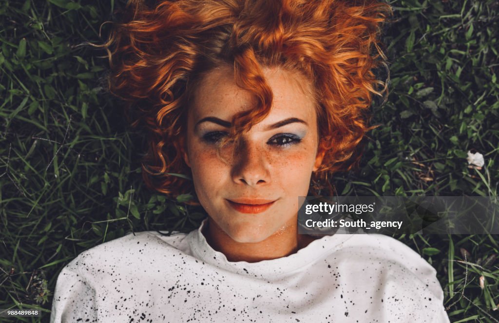 Beautiful young woman lying down in the grass