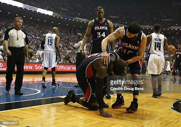 Josh Smith of the Atlanta Hawks is comforted by teammates Mike Bibby and Jason Collins as official Tom Washington looks on after taking an elbow from...