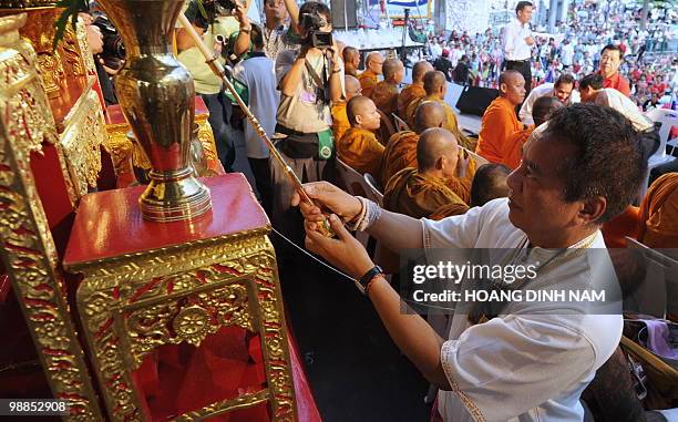 Thai "Red Shirt" anti-government protest leader Veera Musikapong holds a candle in front of a Buddha at the beginning of a ceremony, part of...