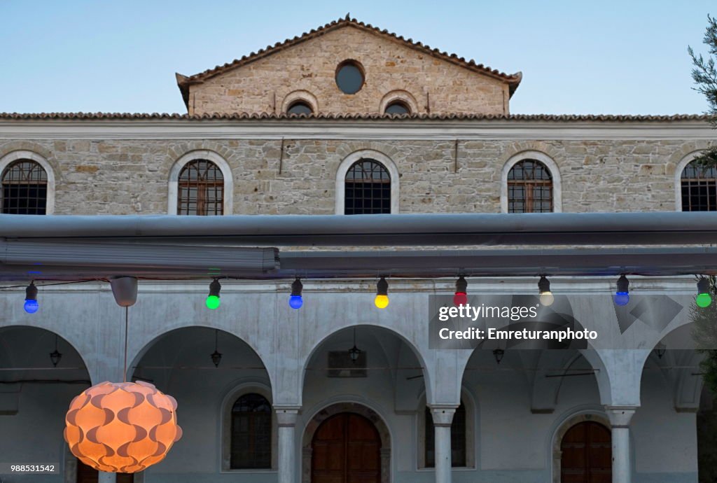 Front facade of Alacati mosque with colored lamps .