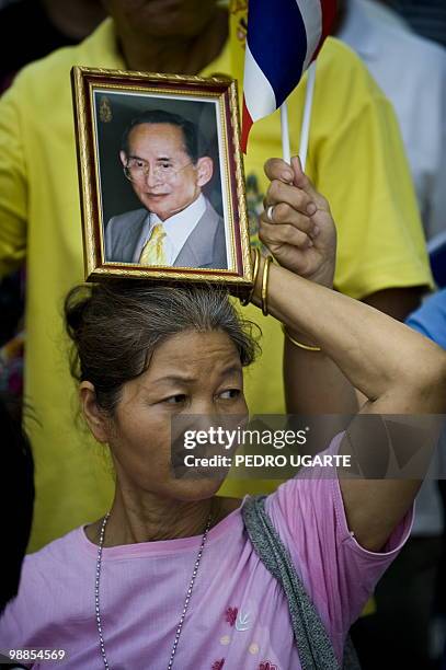 Thai woman holds a portrait of King Bhumibol Adulyadej as she waits with others for him to arrive at the Royal Grand Palace to celebrate his 60th...