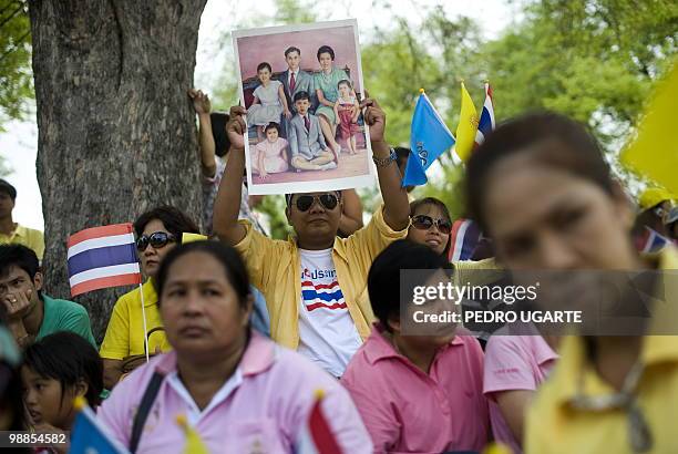 Thai man holds a painting of the Thai Royal family as he waits with others for the arrival of King Bhumibol Adulyadej outside the Royal Grand Palace...