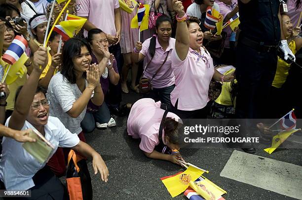 Thai women wave national flags and kneel as the car carrying King Bhumibol Adulyadej passes as he arrives at the Royal Grand Palace to celebrate his...