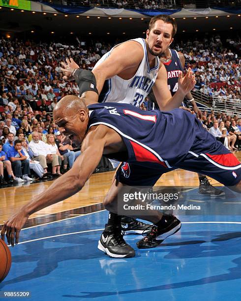 Maurice Evans of the Atlanta Hawks dives for a loose ball as Ryan Anderson of the Orlando Magic reacts in Game One of the Eastern Conference...