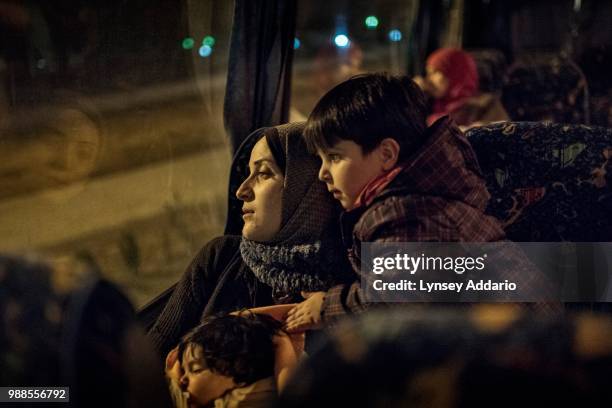 Syrian refugee Tayma Abzali sits with her two children: baby Helen, 4 months old, and Wael, 3 years old, as they ride the bus with other refugee...