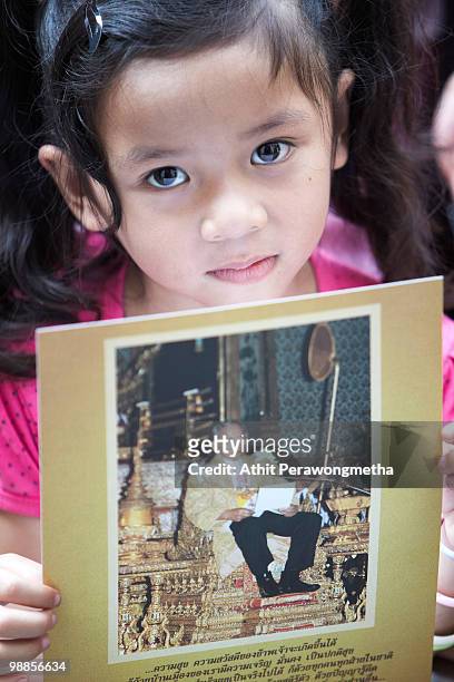 Well-wisher holds a picture of Thai King Bhumibol Adulyadej as she marks the 60th anniversary of his coronation at Siriraj Hospital on May 5, 2010 in...