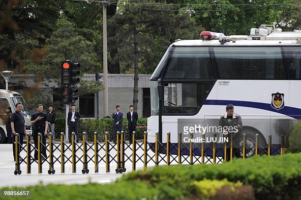 Policemen attempt to use a police bus to block the street in front of Diaoyutai State Guest House as a diplomactic motorcade arrives in Beijing on...