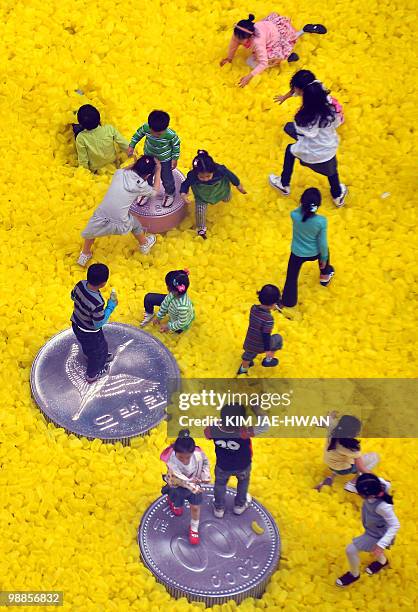 South Korean children play on a field of large plastic coins and cash deposit bags in a park in Seoul on May 5, 2010. South Korea's economy grew a...