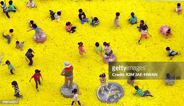 South Korean children play on a field of large plastic coins and cash deposit bags in a park in Seoul on May 5, 2010. South Korea's economy grew a...