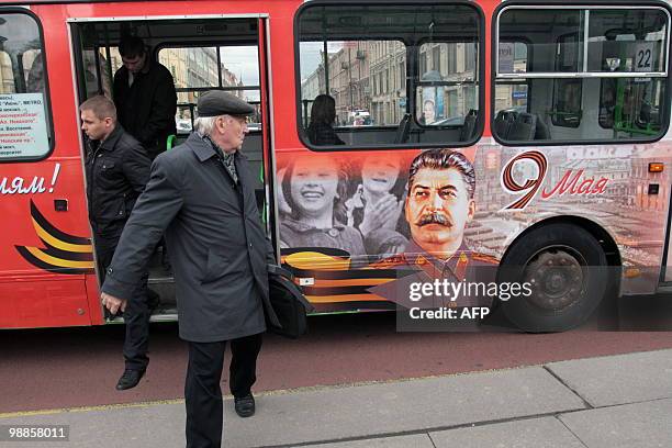 Russians exit a public bus decorated for 65th anniversary Victory Day celebrations bearing a portrait of Soviet dictator Josef Stalin in St....