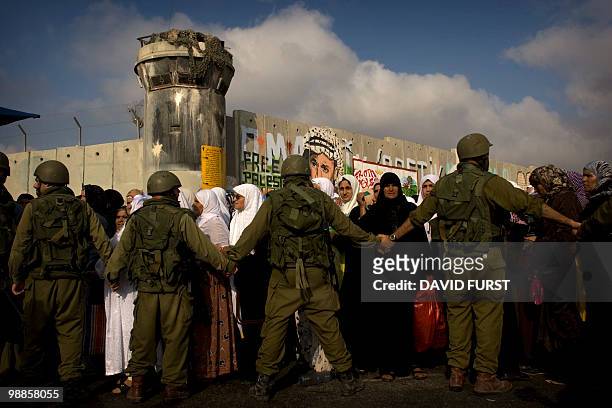 Israeli soldiers stand guard as Palestinian Muslim worshippers wait to cross through the West Bank checkpoint of Qalandia into Jerusalem to attend...