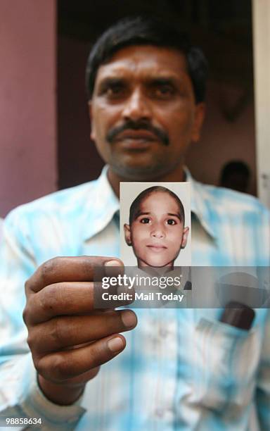 Durga Prasad, the father of seven-year-old Aarti, a victim of Nithari killings, showing her photograph after a special CBI court's verdict on his...