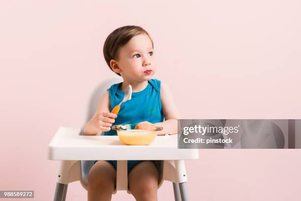 baby isst babynahrung. - baby spielt mit essen stock-fotos und bilder