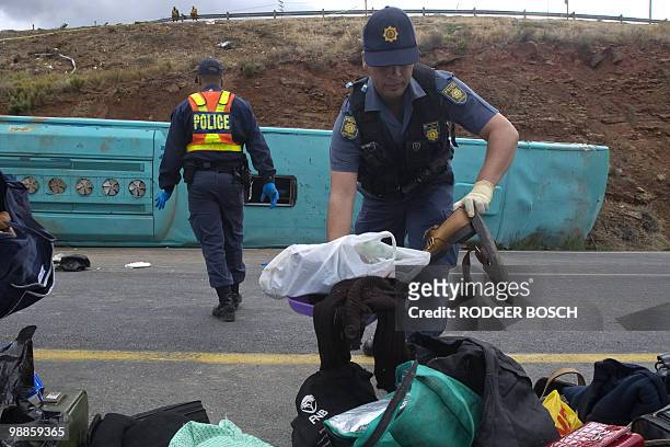 South African policeman removes personal effects on the site of a bus accident on the N1 on May 5, 2010 between De Doorns and Touws river some 150...