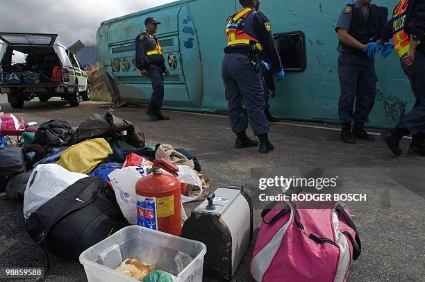 South African policemen remove personal effects on the site of a bus accident on the N1 on May 05, 2010 between De Doorns and Touws river some 150...