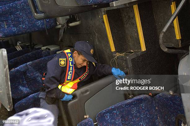 South African police officer climbs in the wreckage of a bus after its accident on the N1 on May 5, 2010 between De Doorns and Touws River some 150...