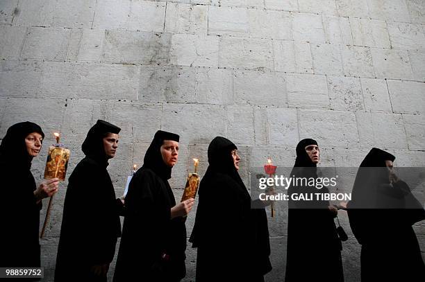 Christian Orthodox nuns holding candles and flowers walk on August 25, 2009 along the narrow streets of Jerusalem's Old City in a religious...