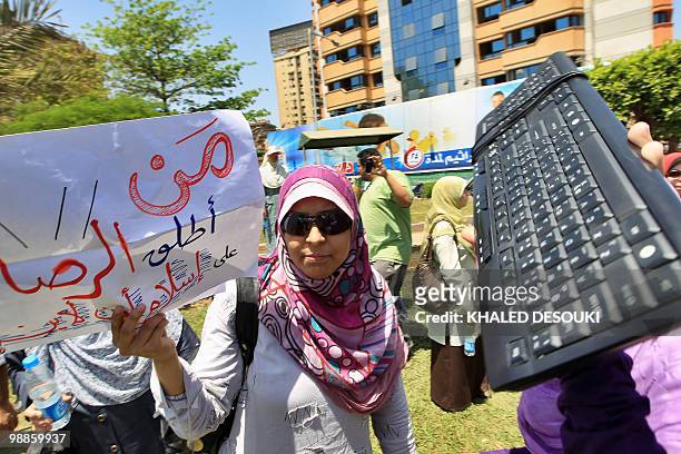 An Egyptian reporter for Islam Online holds a sign as a colleague raises a keyboard outside the Qatari embassy in Cairo on May 5, 2010 during a...