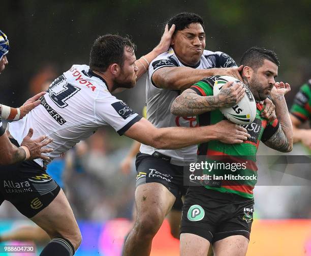 Adam Reynolds of the Rabbitohs is tackled by Jason Taumalolo and Gavin Cooper of the Cowboys during the round 16 NRL match between the South Sydney...