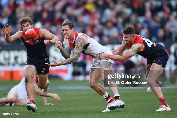 Tim Membrey of the Saints handballs whilst being tackled by Joel Smith of the Demons during the round 15 AFL match between the Melbourne Demons and...