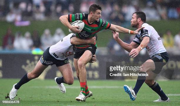 Campbell Graham of the Rabbitohs is tackled by Gavin Cooper and Lachlan Coote of the Cowboys during the round 16 NRL match between the South Sydney...