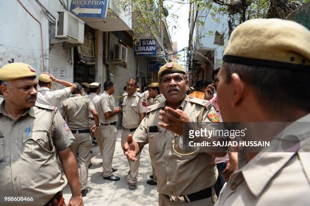 Indian policemen secure the area near a building where 11 family members were found dead inside their home in the neighbourhood of Burari in New...