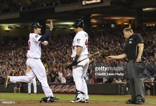 Hardy of the Minnesota Twins is congratulated by Wilson Ramos on scoring the game winning run on a wild pitch from Ryan Perry of the Detroit Tigers...