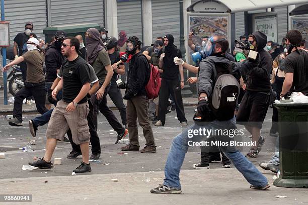 Protesters throw missles at Greek riot police as they clash on May 5, 2010 in Athens, Greece. Three people have died after protesters set fire to the...