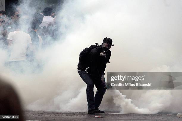 Protester returns a Greek riot police deployed tear gas canister on May 5, 2010 in Athens, Greece. Three people have died after protesters set fire...