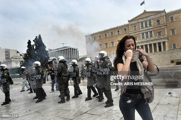 Woman runs away from tear gas during clashes near the Parliament building in the center of Athens on May 5, 2010. A nationwide general strike gripped...