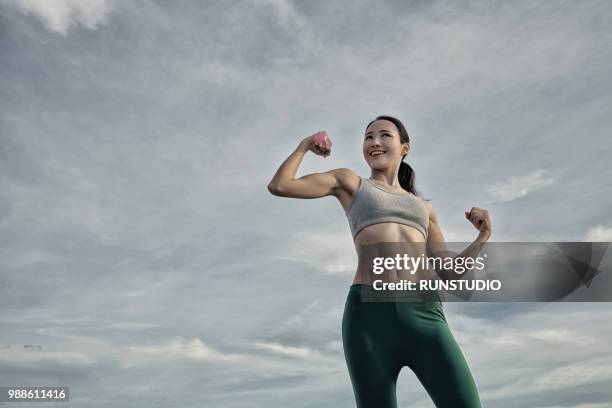 young woman lifting dumbbell outdoors - healthy body stock pictures, royalty-free photos & images