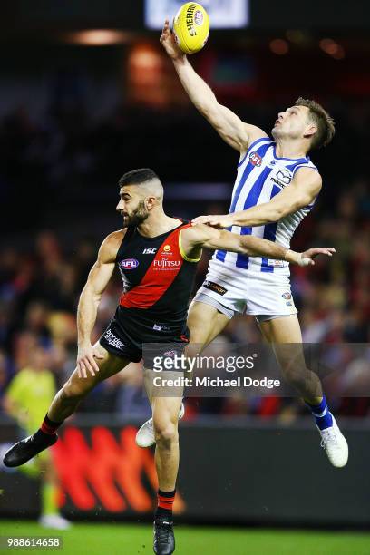 Shaun Higgins of the Kangaroos competes for the ball against Adam Saad of the Bombers during the round 15 AFL match between the Essendon Bombers and...