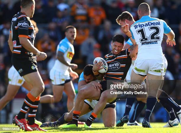 Malakai Watene-Zelezniak of the Tigers is tackled by Titans defense during the round 16 NRL match between the Wests Tigers and the Gold Coast Titans...