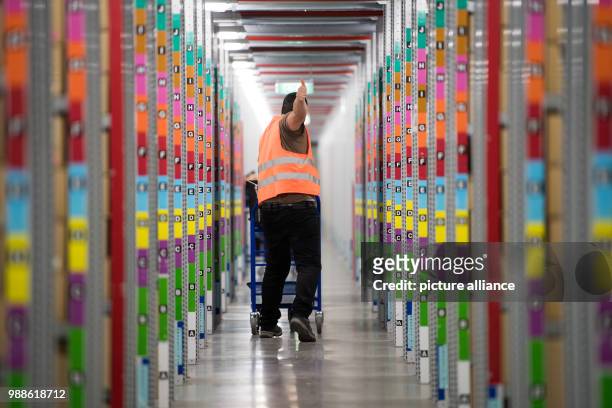 An employee walks through rows of filled shelves during open media day of the electronic commerce giant Amazon, in Bad Hersfeld, Germany, 7 December...