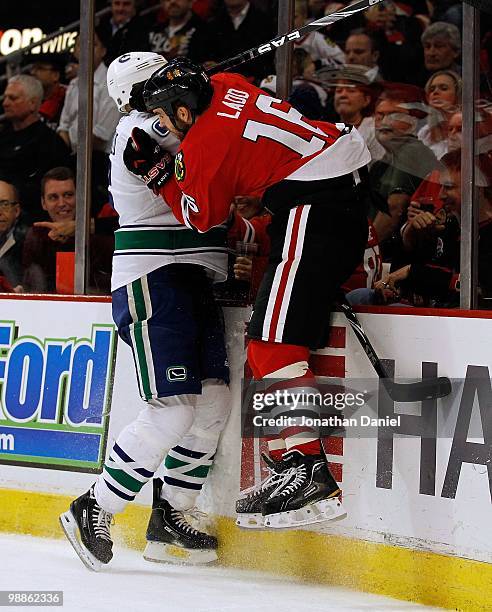 Andrew Ladd of the Chicago Blackhawks tries to check Sami Salo of the Vancouver Canucks into the boards behind the net in Game Two of the Western...